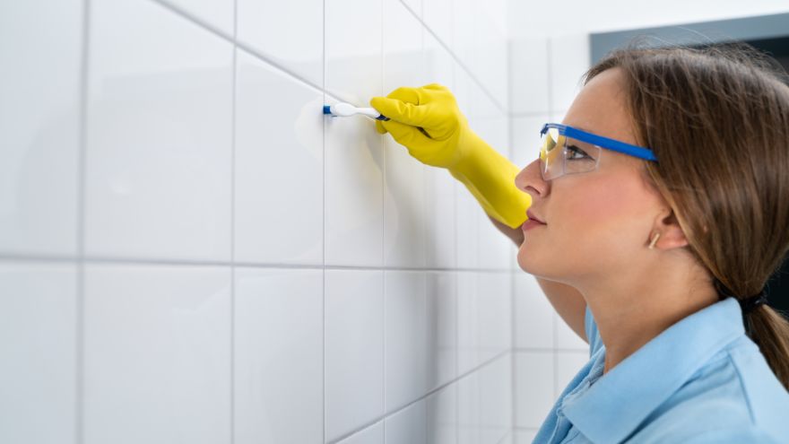 Kobieta czyszcząca fugi w łazience za pomocą szczoteczki