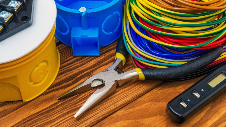 Плоскогубці, що лежать поруч із барвистими кабелями