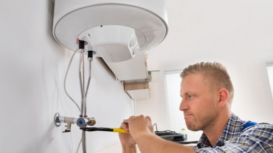 Instalator dokręcający część bojlera elektrycznego