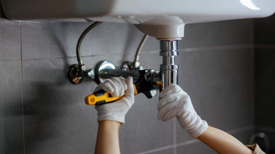 Instalator odkręca zawór spustowy w umywalce