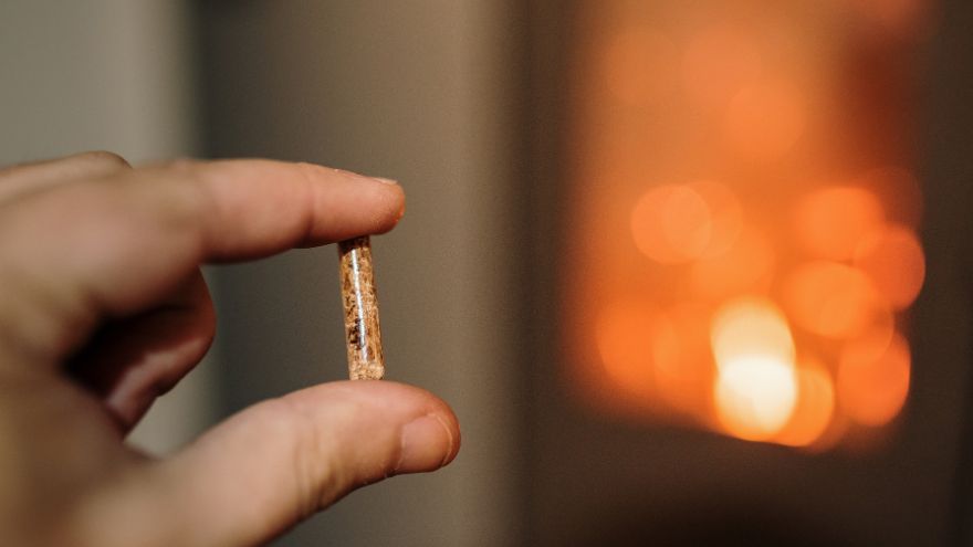 Долоня, що тримає пелет на фоні печі