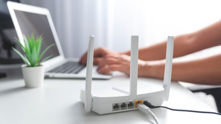 Router wifi blanco sobre un escritorio con una laptop