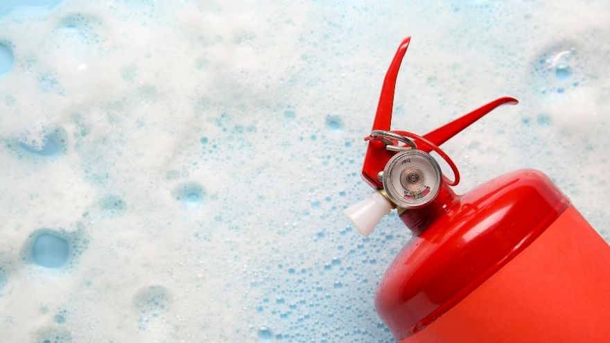 Extincteur rouge sur fond de mousse blanche