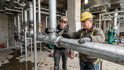 Dwóch hydraulików w kaskach ochronnych montuje instalację