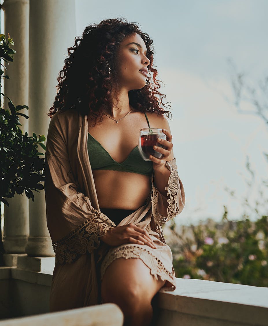 Woman drinking wine while sitting on ledge and looking out