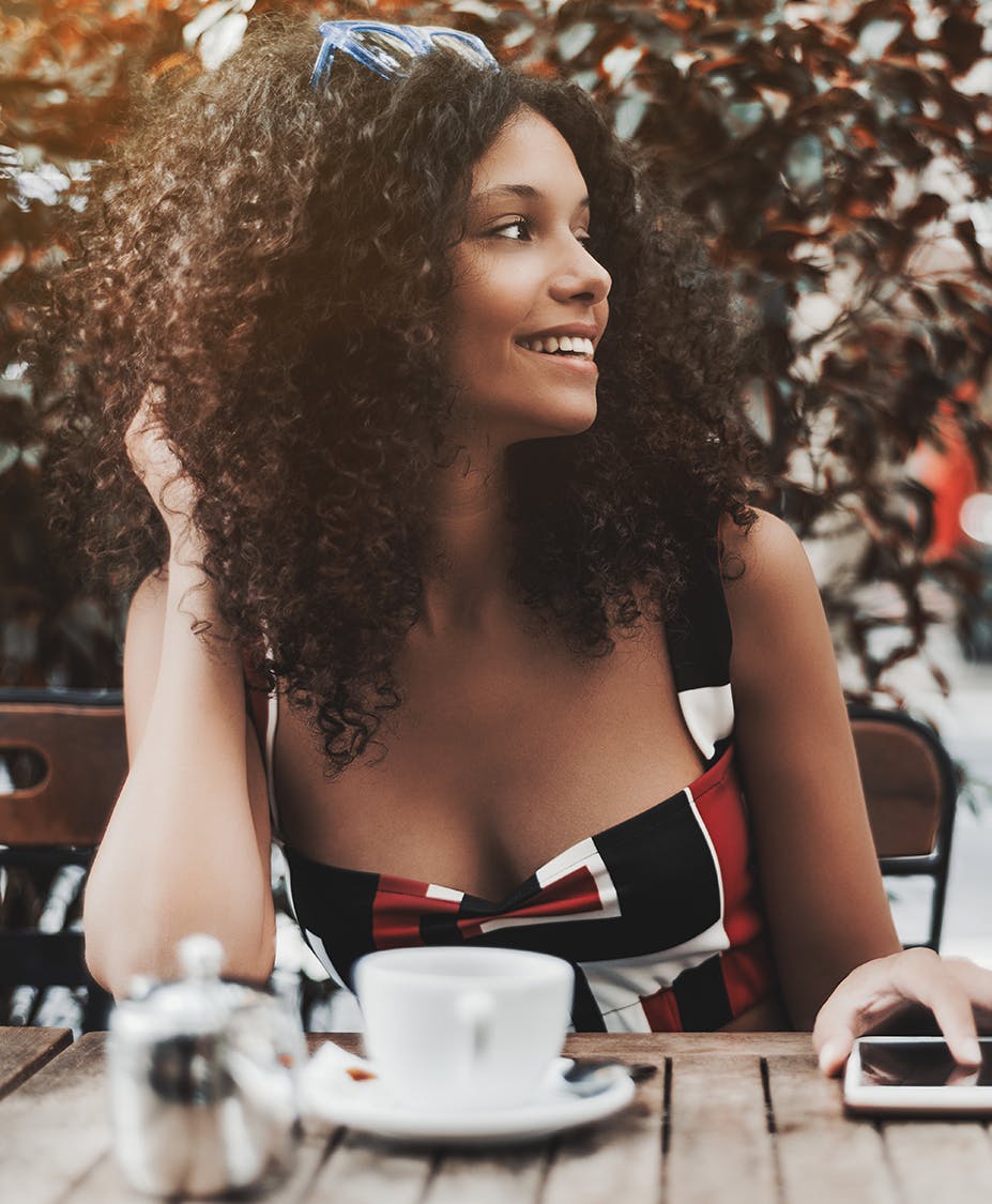 Woman sitting outside at a table with her hand in her hair