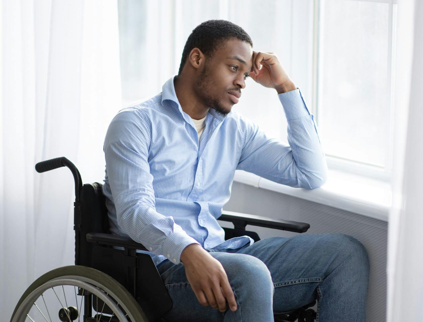 man in wheelchair looking out window