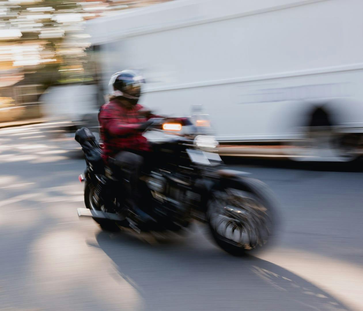 motorcyclist riding past a truck