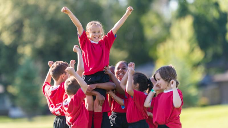 Group of children in soccer uniforms cheering
