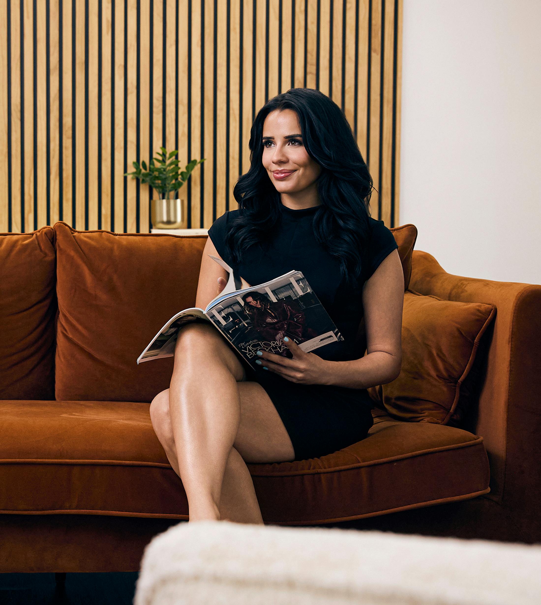 woman sitting on a couch holding a magazine
