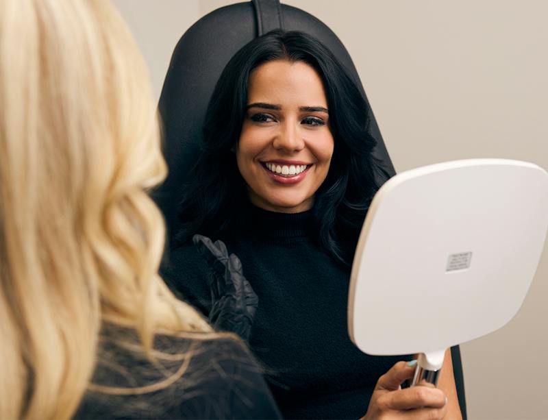 Woman smiling holding a mirror