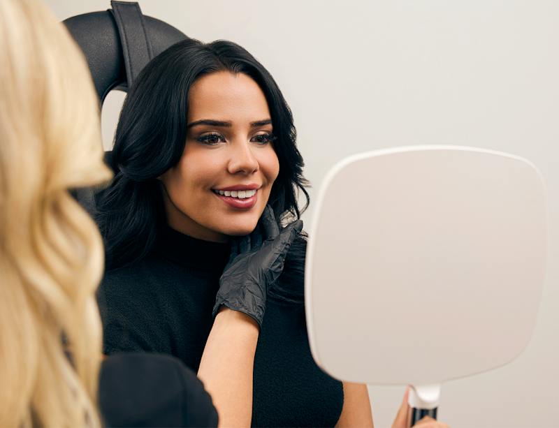 woman looking at her face in a hand mirror