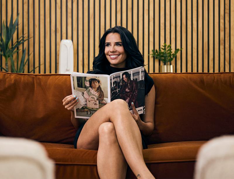 woman smiling on the couch holding a magazine