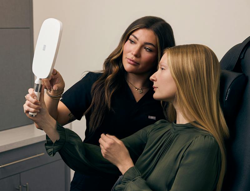 provider and patient looking at her face with a hand mirror