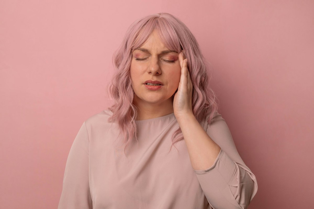 Woman holding her temple with eyes closed due to migraine pain, representing a patient seeking Botox migraine treatment at Geneva Med Spa in Alpharetta