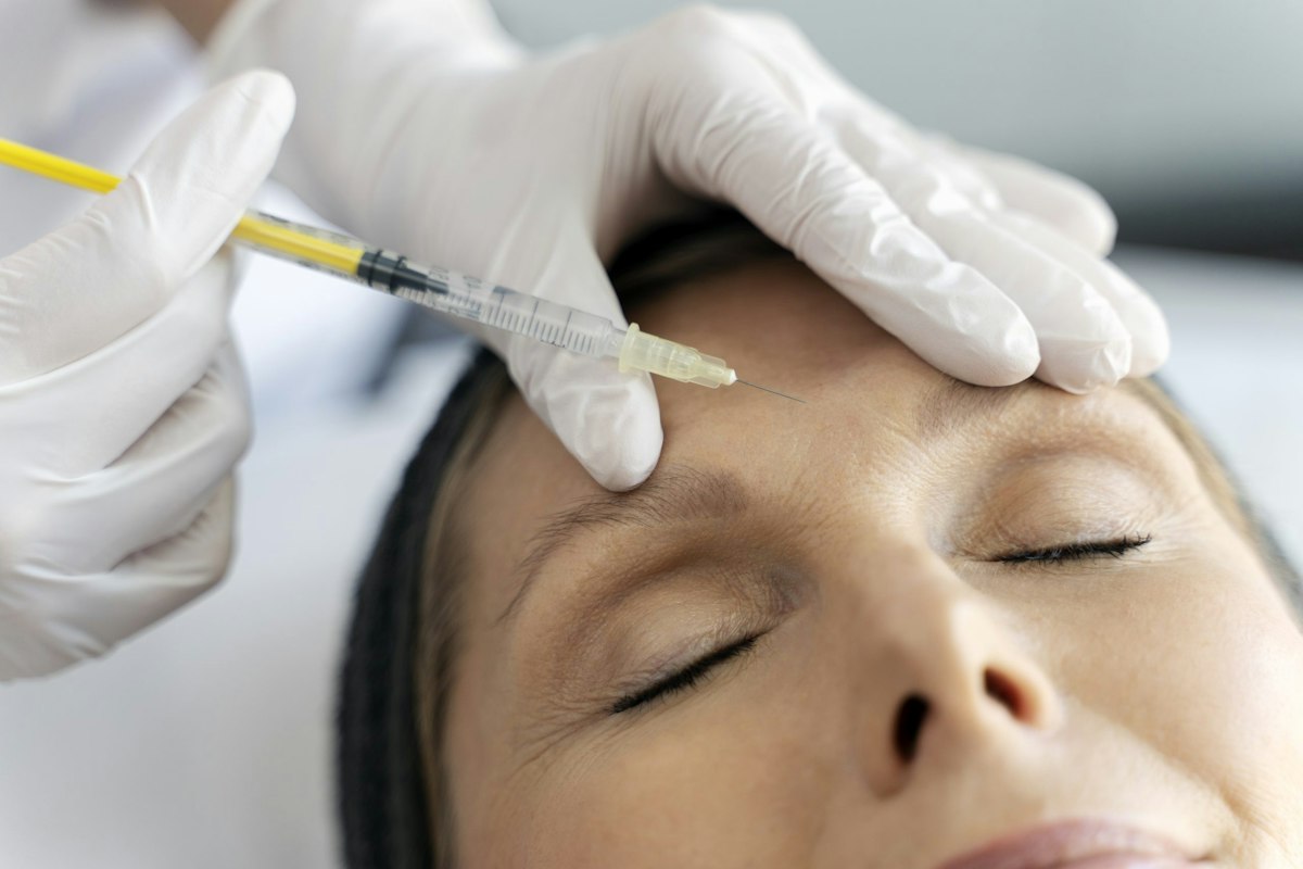 Satisfied patient receiving Botox injection in the forehead during a physician directed cosmetic treatment at a medical spa