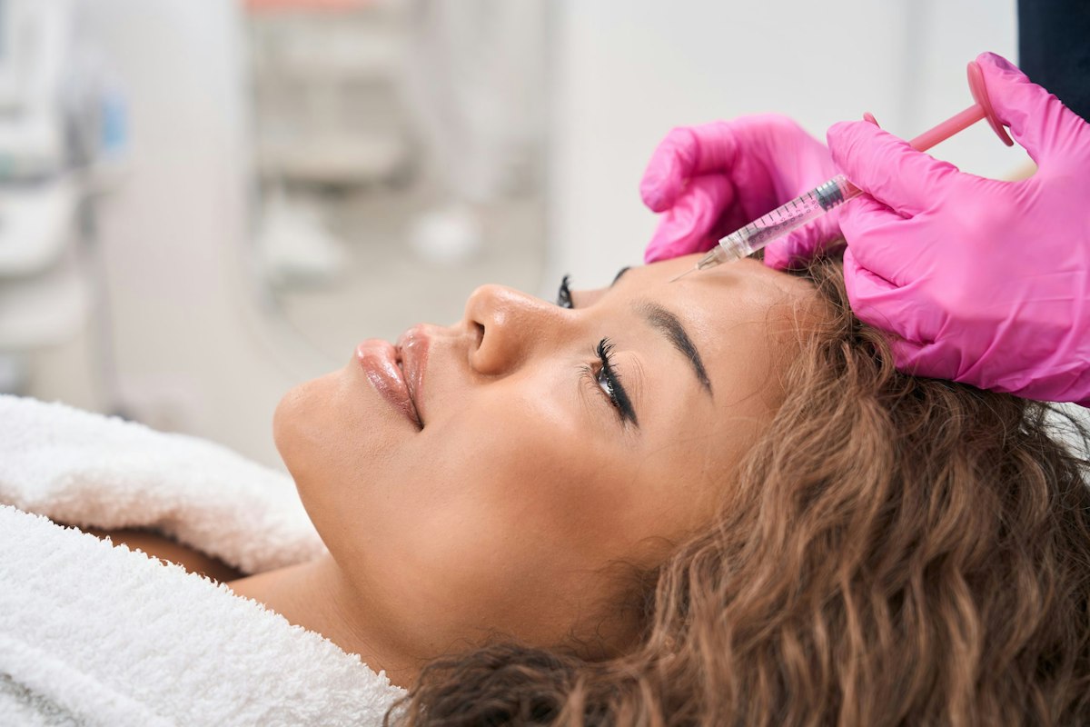 Smiling female patient at Geneva Med Spa receiving Dysport injections in the forehead from a medical provider, showcasing professional aesthetic treatment for wrinkle reduction in Alpharetta.