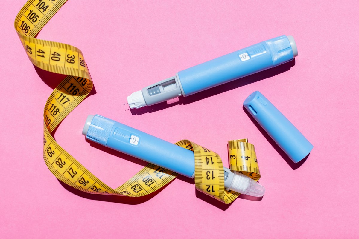 Semaglutide injection pens alongside a measuring tape on a pink background, representing medically supervised weight loss treatment.