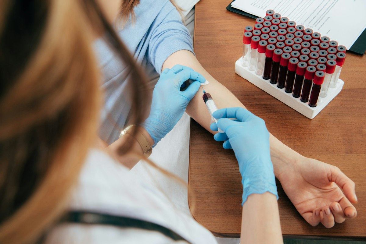 Primary care clinician drawing blood from a patient’s arm for preventive laboratory testing at a medical office