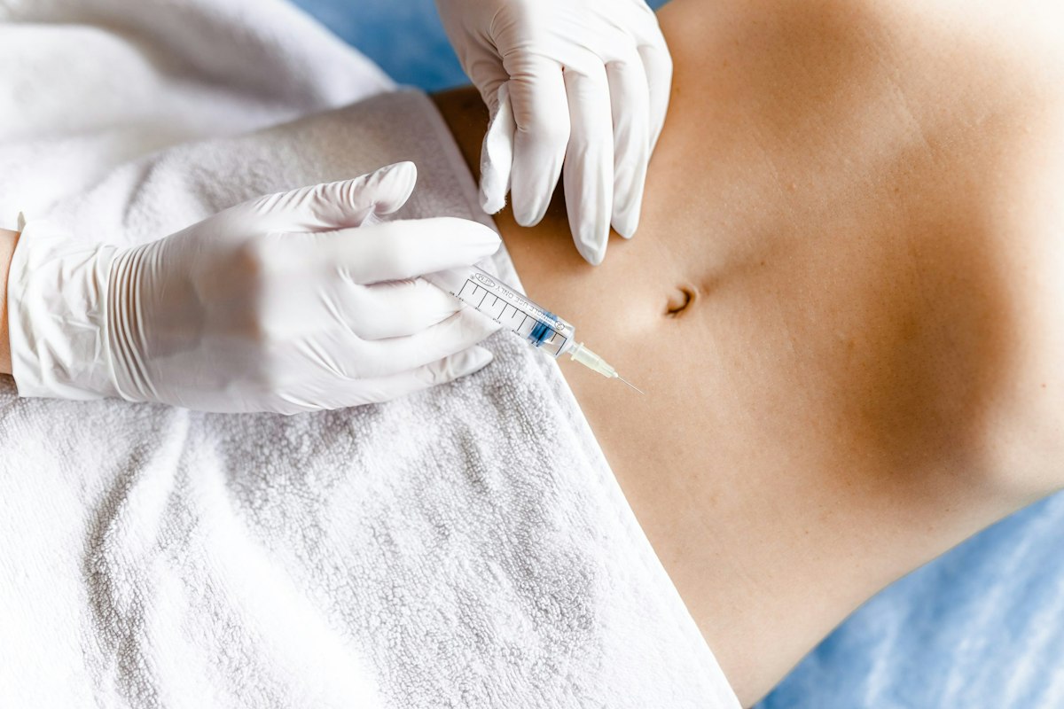 A medical provider wearing gloves administering a GLP 1 weight loss injection into the abdominal area at Geneva Primary Care and Med Spa in Alpharetta.