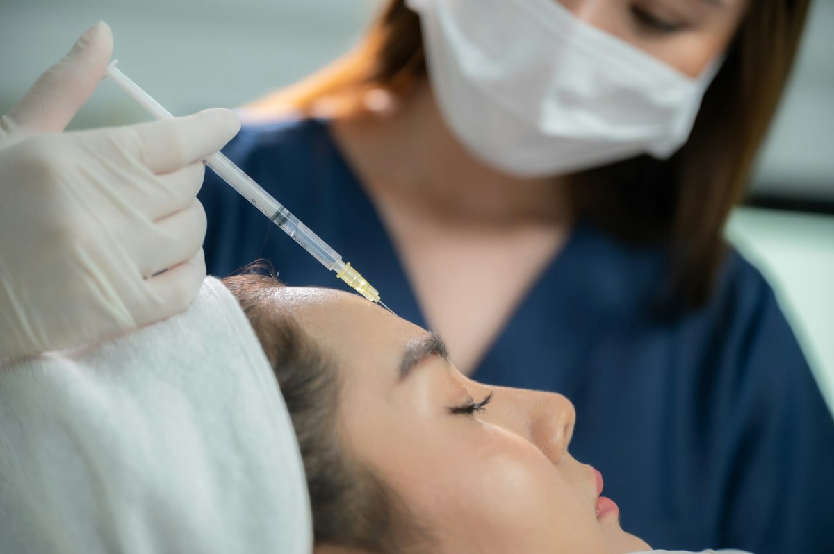 A patient receiving a gentle Botox injection to the forehead at Geneva Primary Care and Med Spa in Alpharetta performed by a medical provider wearing gloves and a mask.