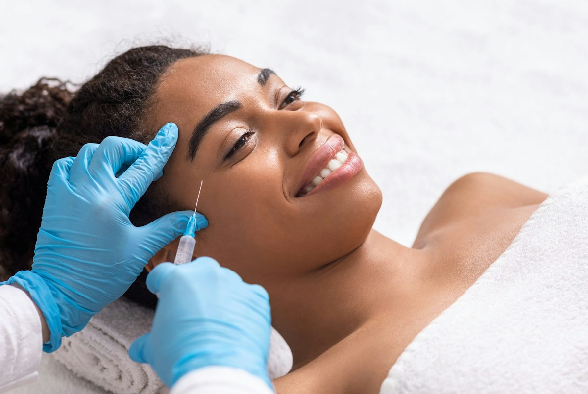 Patient receiving a Botox injection near the eye at Geneva Med Spa in Alpharetta administered by a medical professional wearing blue gloves