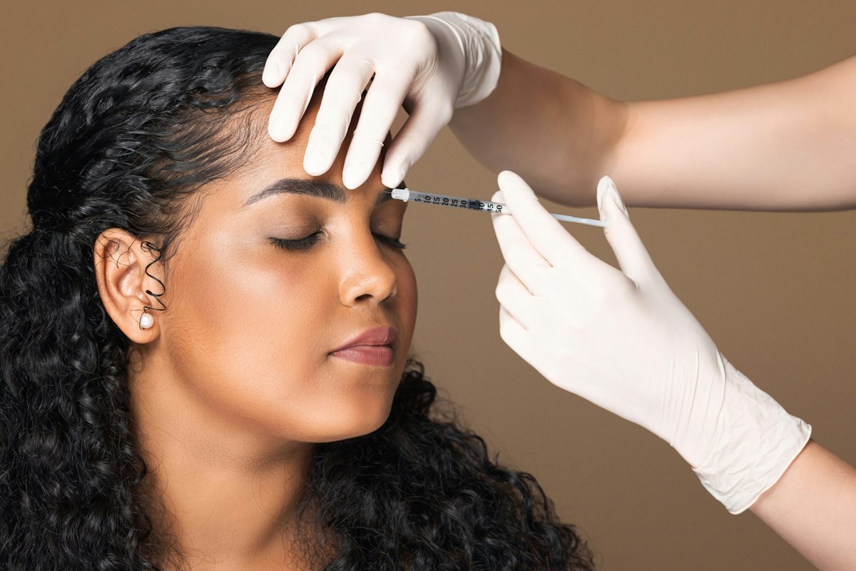 A cosmetologist performing a precise Botox injection in the interbrow area for a Latin woman during a professional treatment at Geneva.