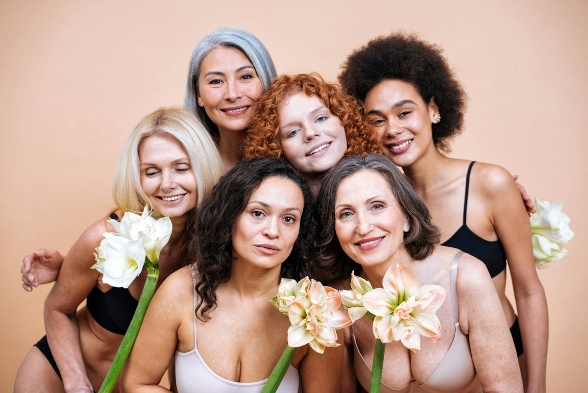 A diverse group of women of different ages, skin tones, and body types standing together to celebrate natural beauty and wellness at Geneva.