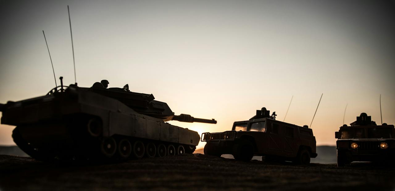 Armored vehicles in silhouette at dusk