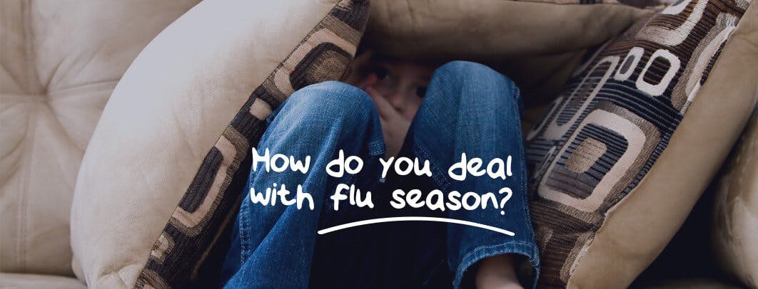 A person is sitting on a beige couch, wearing blue jean, down with flu