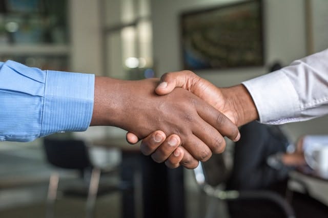 Breach of Employement Contract Office handshake between two individuals signifies a resolution to a breach of contract.