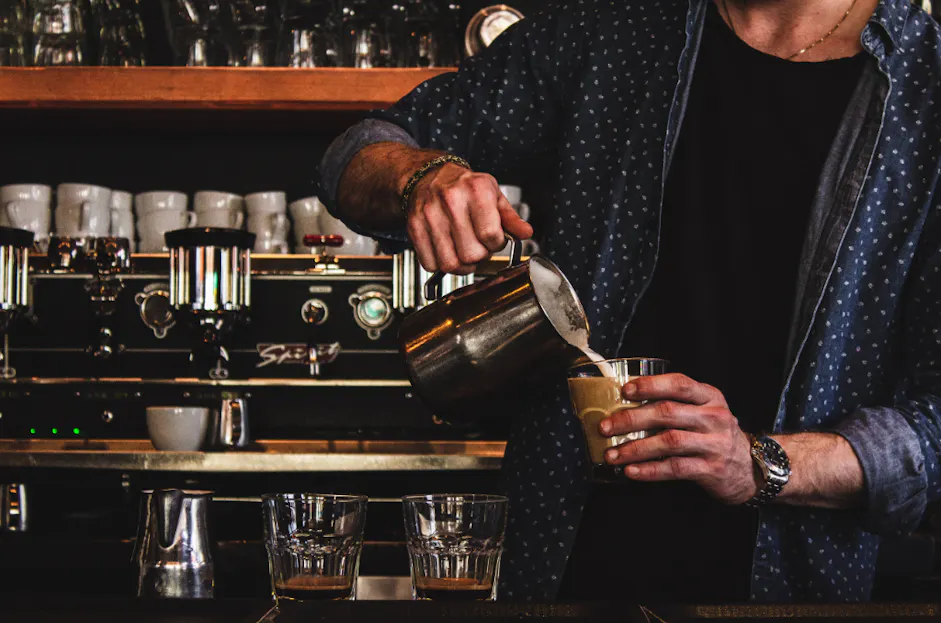 male pouring a latte in a bar