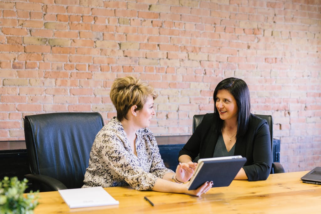 Two female colleagues chatting in an office