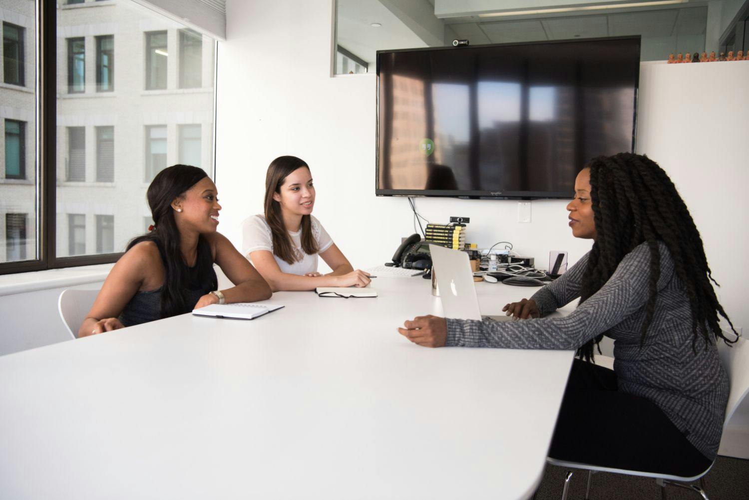 Cultural fit Three women in a meeting room discussing cultural fit of a new hire.