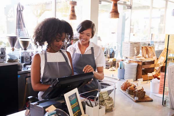 Two cafe workers working on the till