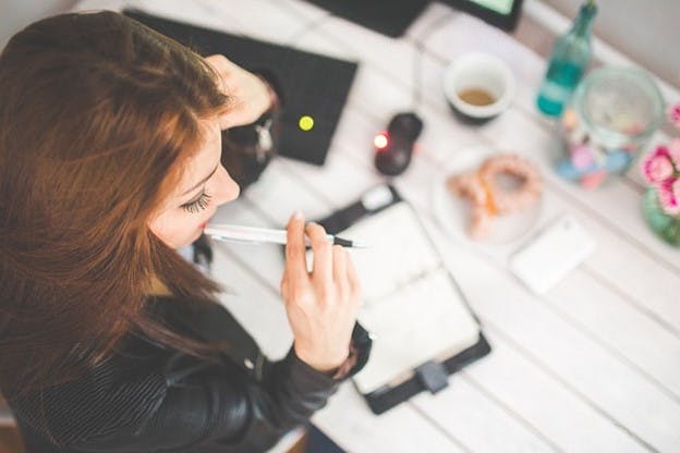 A woman working at a desk with a notebook and pen