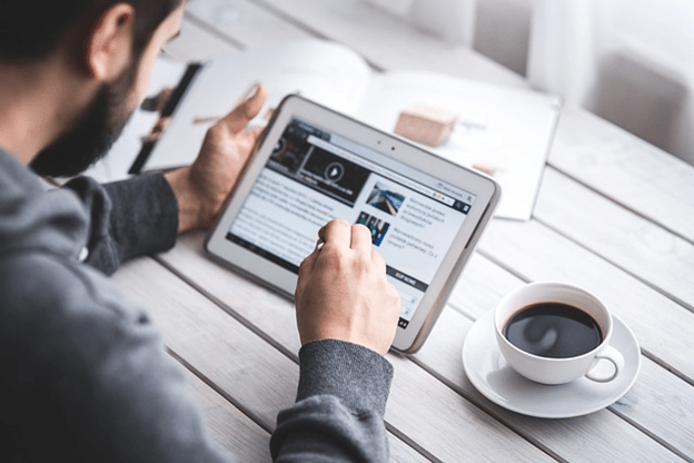 Person using a tablet at a desk with a coffee