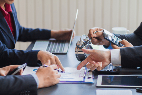 Group of 4 people sat at a desk having a team meeting