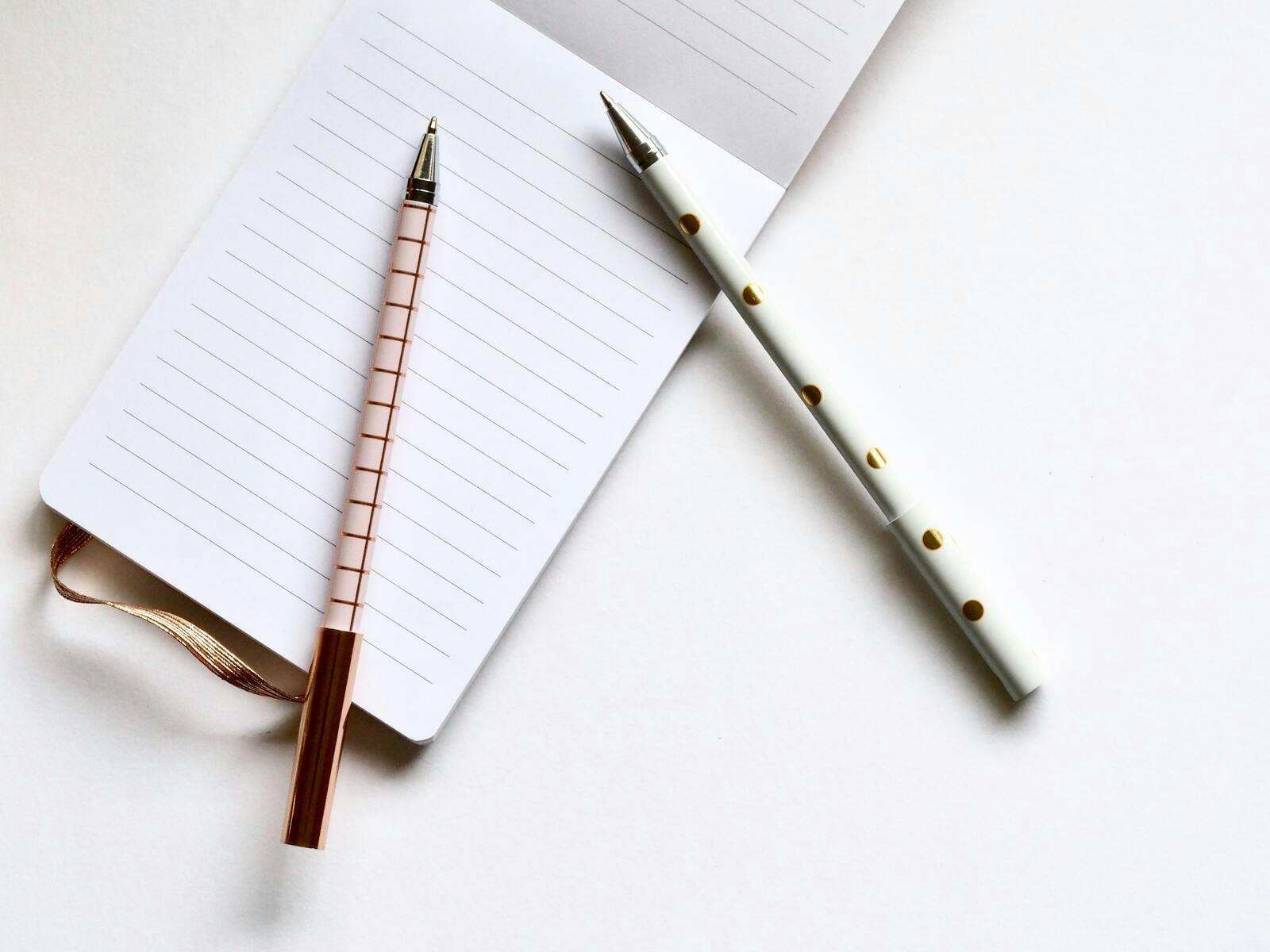 A notepad with two pens resting on it ready for a meeting