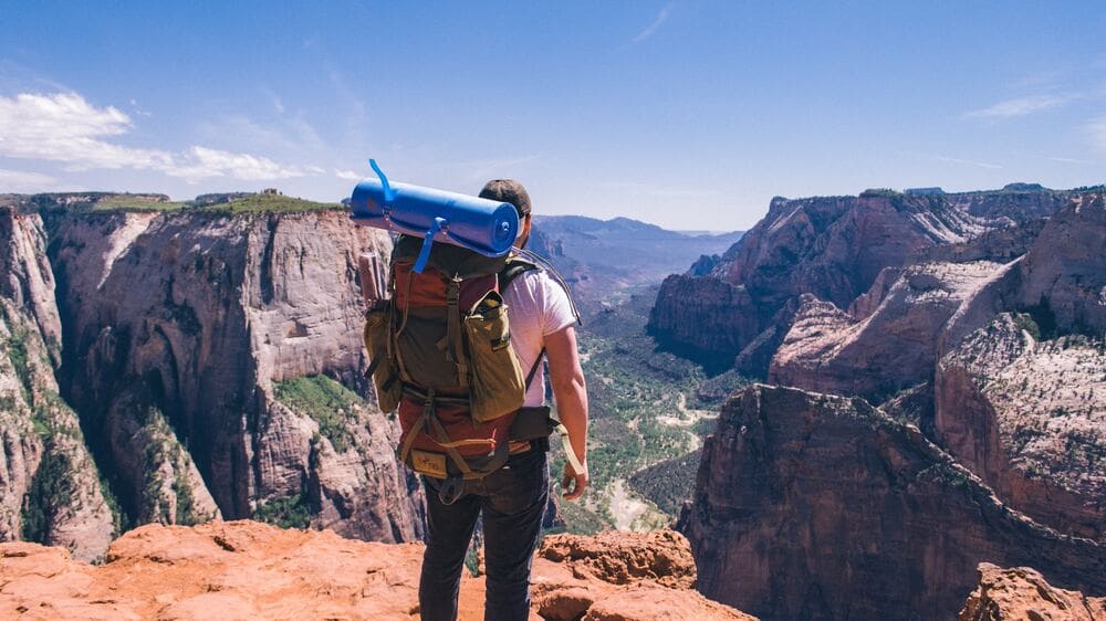 Person with a backpack standing over a canyon on holiday using annual leave