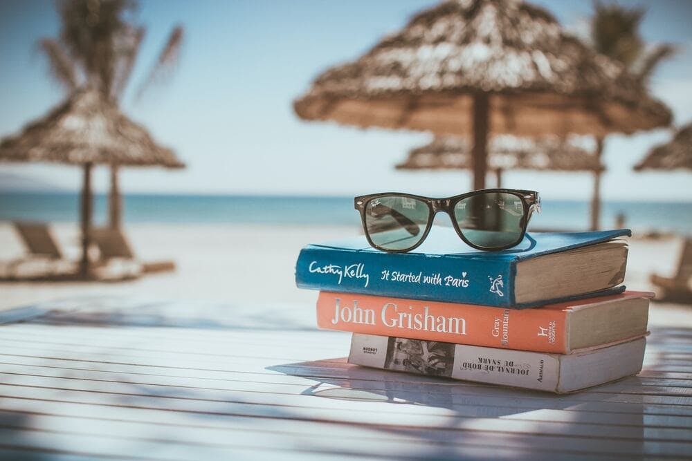 Stack of books and sunglasses on a table at a beach