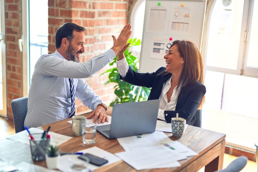 Two people having a high five after a positive employee appraisal review