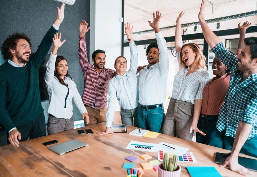 Group of people cheering in an office after a motivational meeting