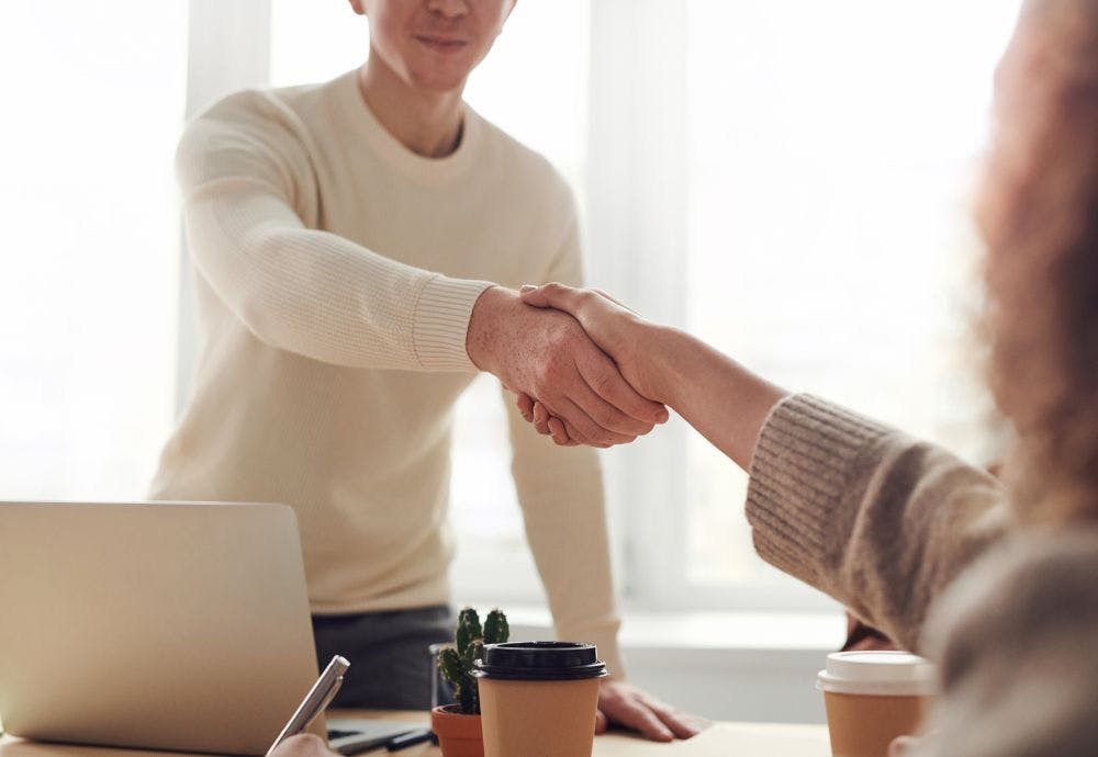 Two people shaking hands after a successful staff appraisal meeting