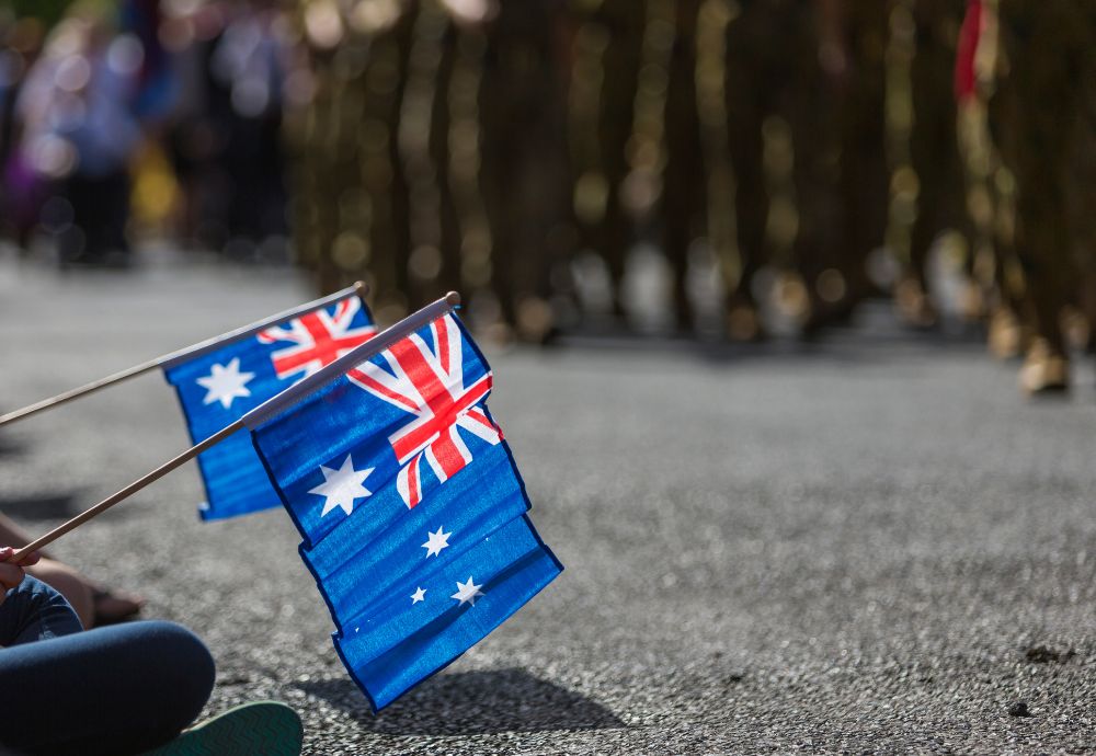 Two Australian flags with people remembering Anzac day