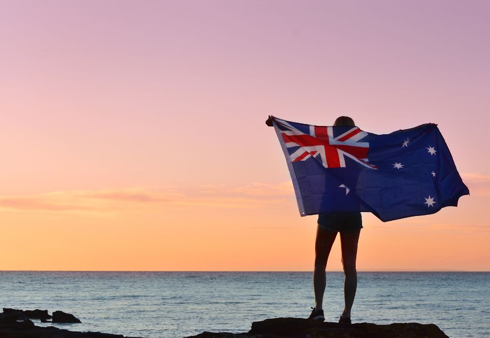 Someone with an Australian flag by the coast celebrating Australia day