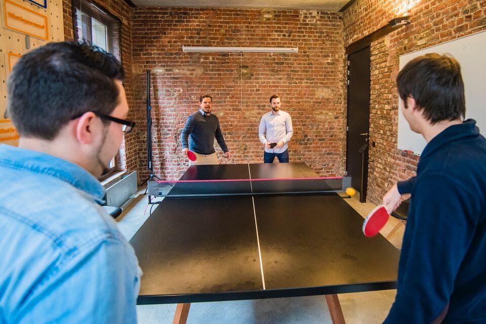 4 people enjoying a work benefit of having table tennis in the office