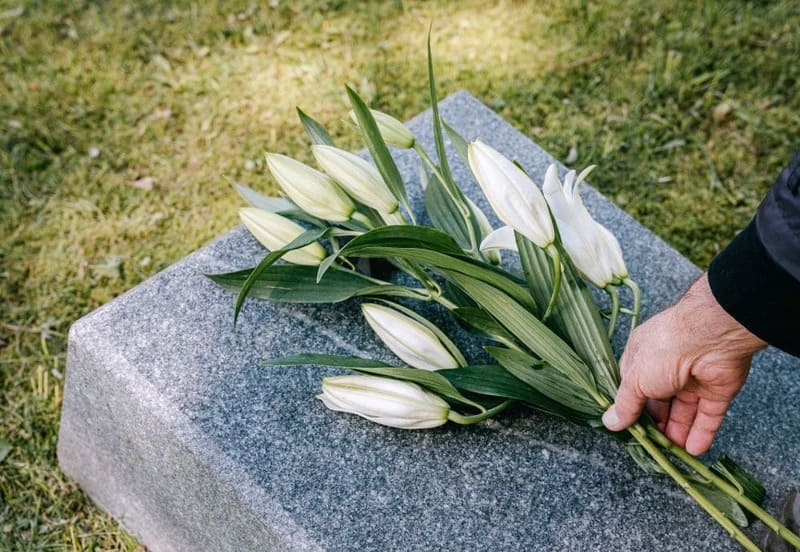 Person on compassionate leave laying flowers on a grave