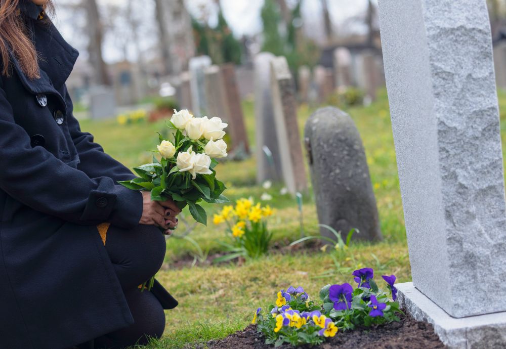 A person placing flowers on a grave due to a recent bereavement