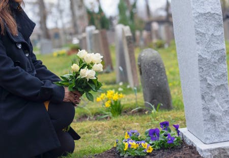 Placing flowers A person placing flowers on a grave due to a recent bereavement